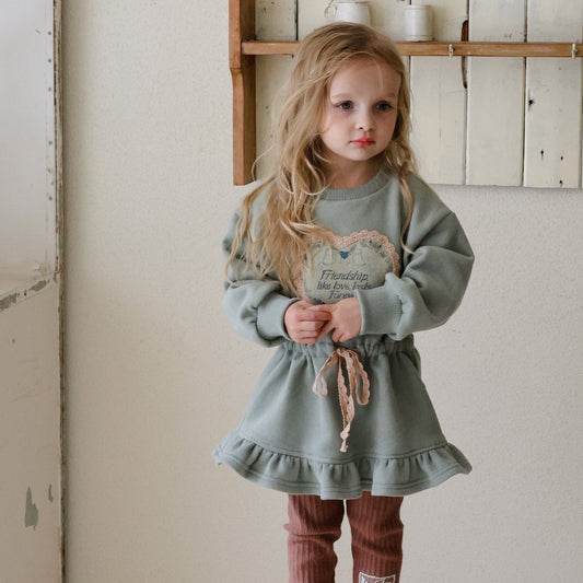 Little girl wearing mint fleece dress with heart patch, cozy winter outfit by Chérubi