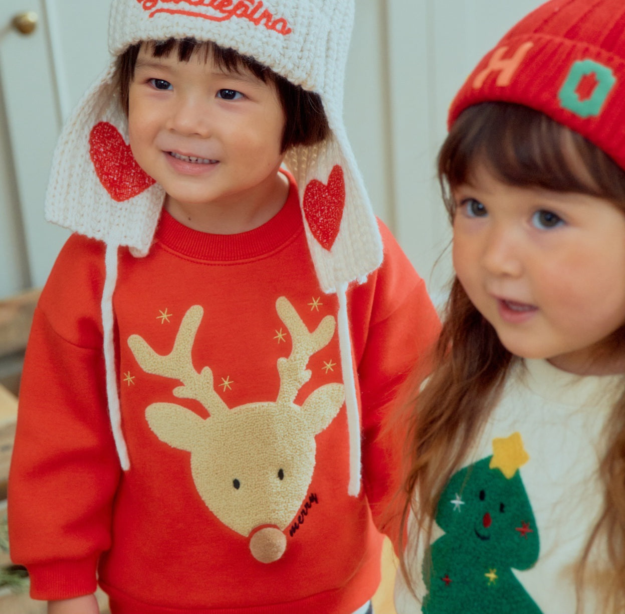Girl wearing cozy fleece-lined Christmas sweatshirt with embroidered reindeer, red and cream
