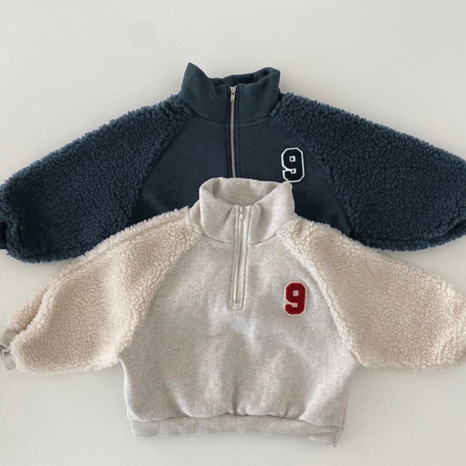 fleece jogger sets in navy blue and ivory, featuring half-zip tops with number 9 embroidery and matching jogger pants, laid flat on a white background.